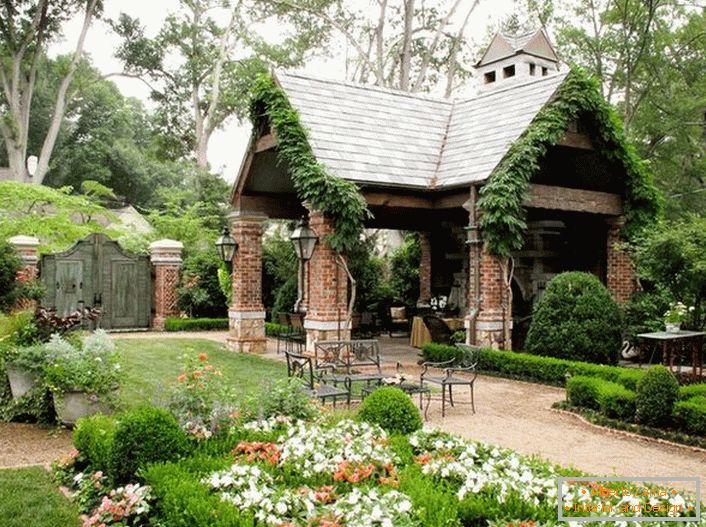 The elegant simplicity of an open gazebo in the style of a chalet looks organically in a luxurious, cozy garden. 